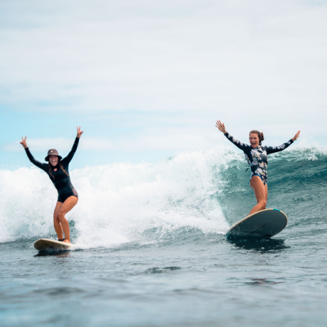 Two women surfing a wave together on San Cristóbal Island